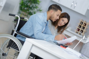 Man and wheelchair and woman sitting at table looking at paperwork